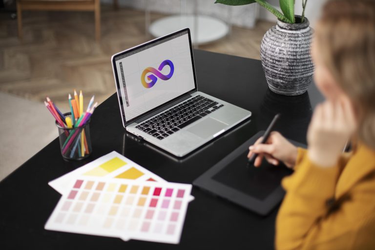 conceptrice de logo feminin travaillant sur sa tablette connectee a un ordinateur portable
