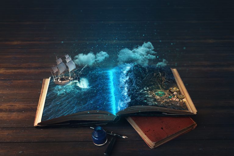 Un livre vintage ouvert avec de belles pages, sur une histoire. Posé proche d'un notebook.